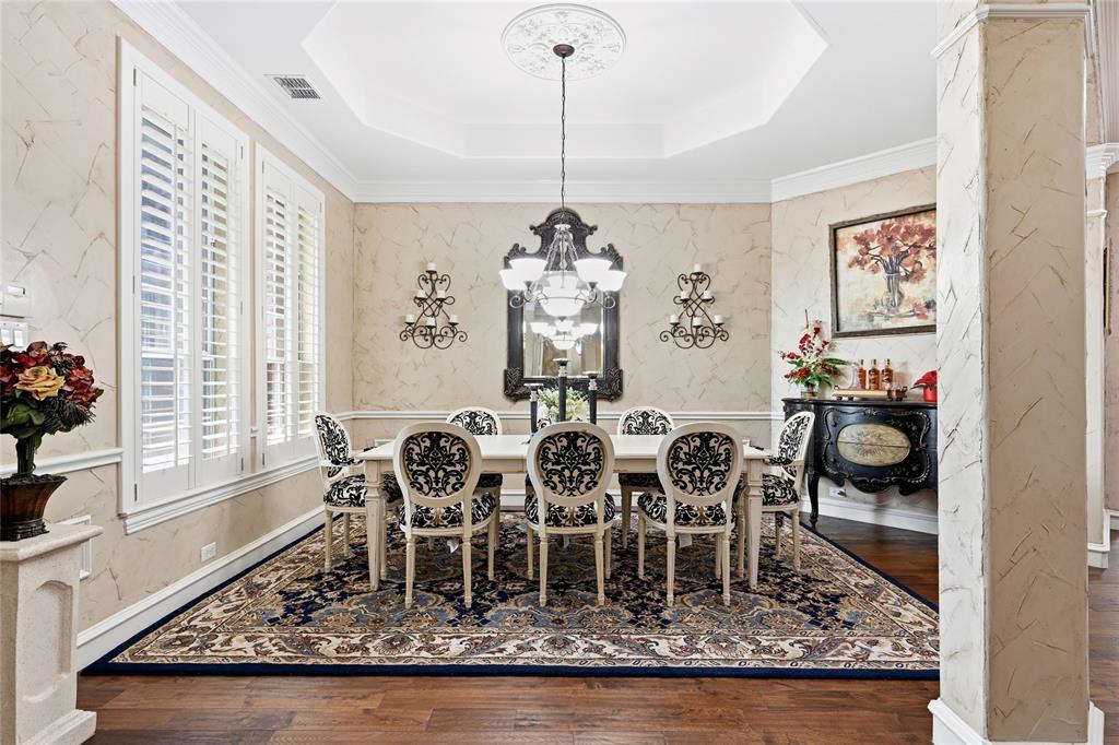 The formal dining room at 102 W Carruth Lane with a stepped tray ceiling, a black chandelier and ceiling medallion, damask-upholstered chairs, and hardwood floors